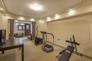A home gym with exercise equipment, a television, and a sofa in the background. - Villa Verity - Nine Bedroom Villa, Sleeps 21 (Porto Germeno)