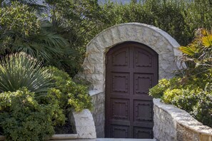 A stone archway leading to a dark wooden door, surrounded by lush greenery.