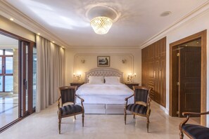 A spacious bedroom with a large bed, two upholstered chairs, a chandelier, and a painting on the wall. - Villa Verity - Nine Bedroom Villa, Sleeps 21 (Porto Germeno)