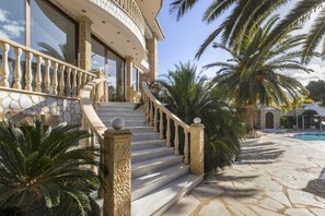A grand staircase leading to a building with a stone facade and a pool area with palm trees. - Villa Verity - Nine Bedroom Villa, Sleeps 21 (Porto Germeno)