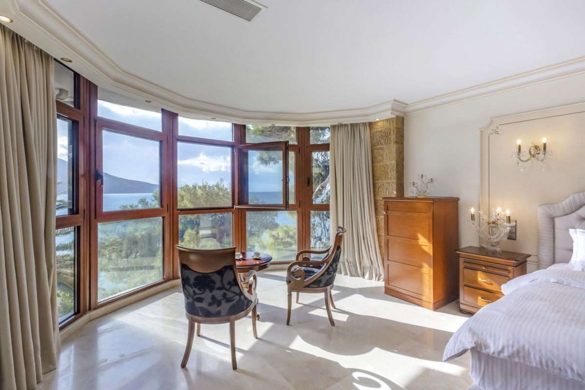 Une chambre avec une grande fenêtre, un lit, une table de chevet et une commode.