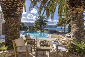 A pool area with lounge chairs and a view of the sea.