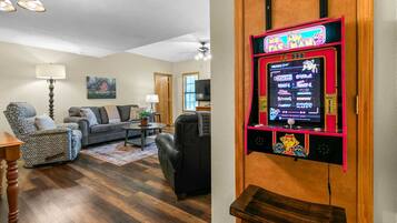 Una sala de estar con una máquina arcade retro, un sofá, una mesa de centro y una lámpara.