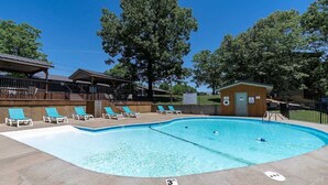 Une piscine équipée de chaises longues, d’un poste de surveillance pour les sauveteurs et d’un espace couvert avec des escaliers.