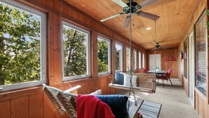 L’intérieur d’une cabane comprend un coin repas, un fauteuil suspendu et de grandes fenêtres.