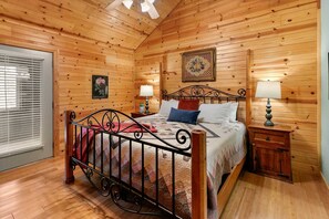 A wooden-paneled bedroom with a bed, bedside lamps, and a window with blinds.