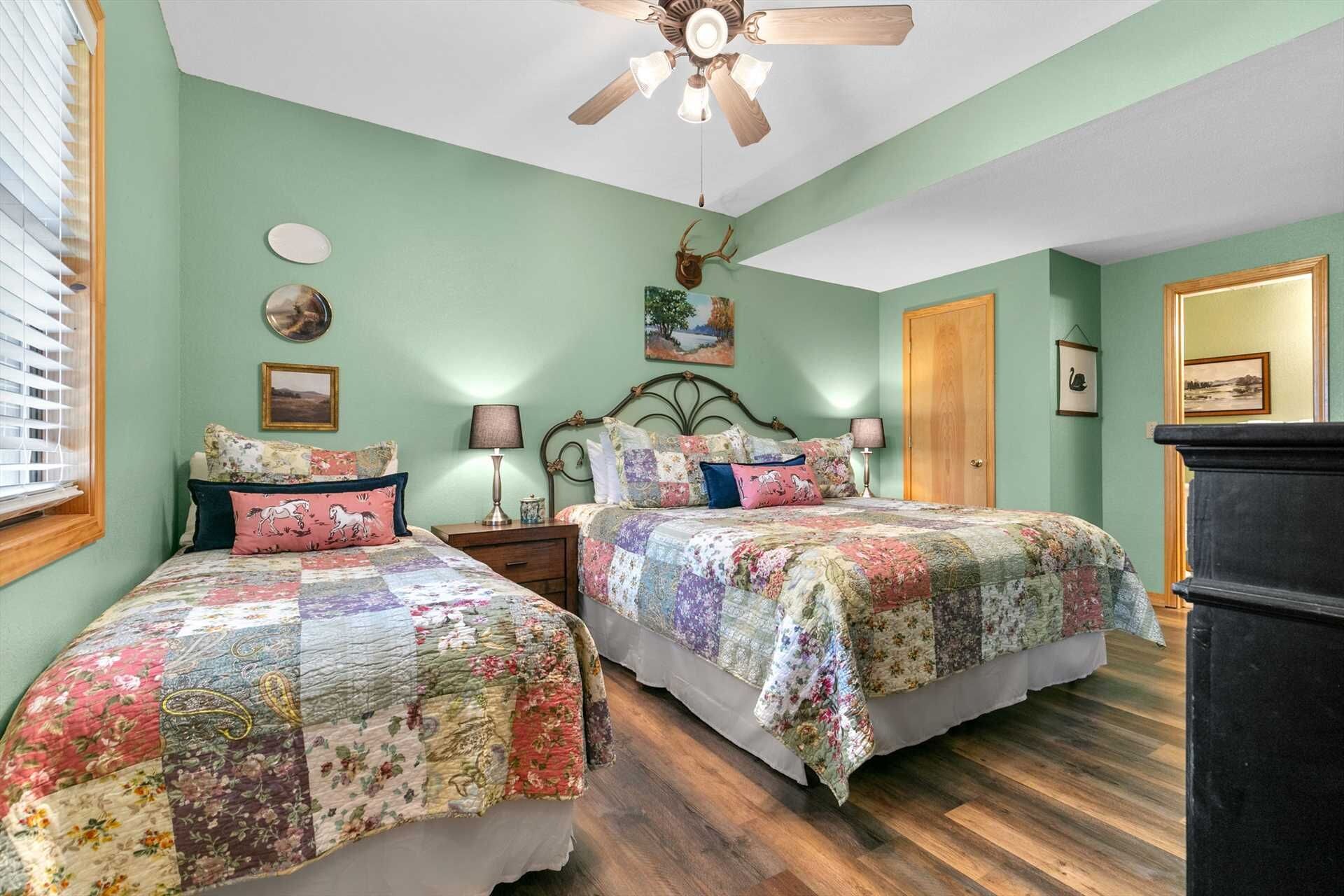 A bedroom with two beds, a ceiling fan, and a dresser.
