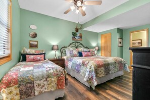 Un dormitorio con dos camas, ventilador de techo y cómoda.
