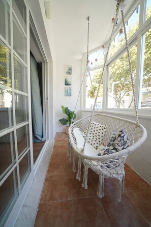 A room with a hanging chair, a window with a view, and a door. - Cascais apartment with 2 bedrooms, 70 m², and a sunny terrace! (Cascais)