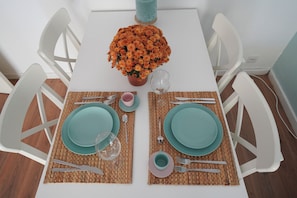 A table set with two plates, cutlery, and a glass, with a potted plant in the center. - Cascais apartment with 2 bedrooms, 70 m², and a sunny terrace! (Cascais)