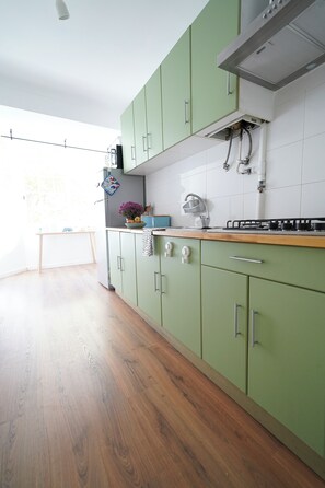 A kitchen with green cabinets, a stainless steel sink, and a wooden countertop. - Cascais apartment with 2 bedrooms, 70 m², and a sunny terrace! (Cascais)