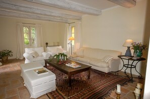 Un salon chaleureux avec un canapé blanc, un fauteuil blanc, une table basse en bois et un tapis à motifs.