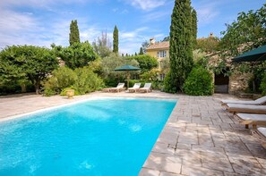 Piscina com espreguiçadeiras e um pátio de pedra.