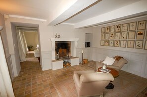 A living room with a fireplace, a sofa, a coffee table, and a wall with framed botanical prints. - Maison Cerisaie - Four Bedroom Villa, Sleeps 8 (Pernes-les-Fontaines)