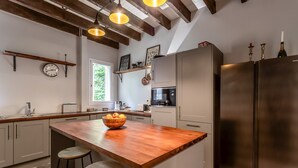 A modern kitchen with a wooden island, stainless steel appliances, and a checkered floor.