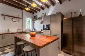 A modern kitchen with a wooden island, stainless steel appliances, and a checkered floor. - Chateau des Pyrenees (Bagnères-de-Luchon)