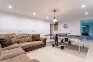 A modern living room with a sofa, a ping pong table, and a clock on the wall. - Chateau des Pyrenees (Bagnères-de-Luchon)