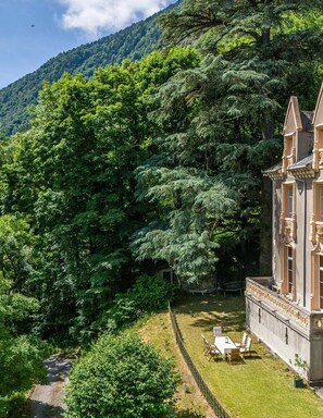 A large building with a formal garden and a view of a forested hillside. - Chateau Des Pyrenees (Bagnères-de-Luchon)