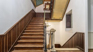 A wooden staircase with a handrail and a chandelier.