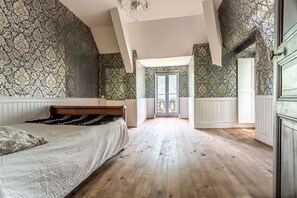Een slaapkamer met een groot bed, houten vloeren en behang met een patroon.