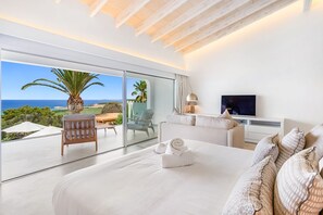Ein modernes Schlafzimmer mit einem großen Bett, einem Fernseher und Meerblick.