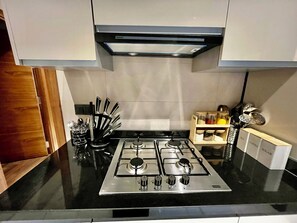 A modern kitchen with a gas stove, stainless steel appliances, and a black countertop. - Apartment Guéliz Prestige (Marrakech)