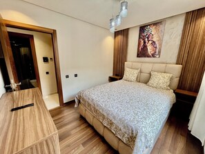 A bedroom with a bed, bedside tables, a wooden desk, and a painting on the wall. - Apartment Guéliz Prestige (Marrakech)