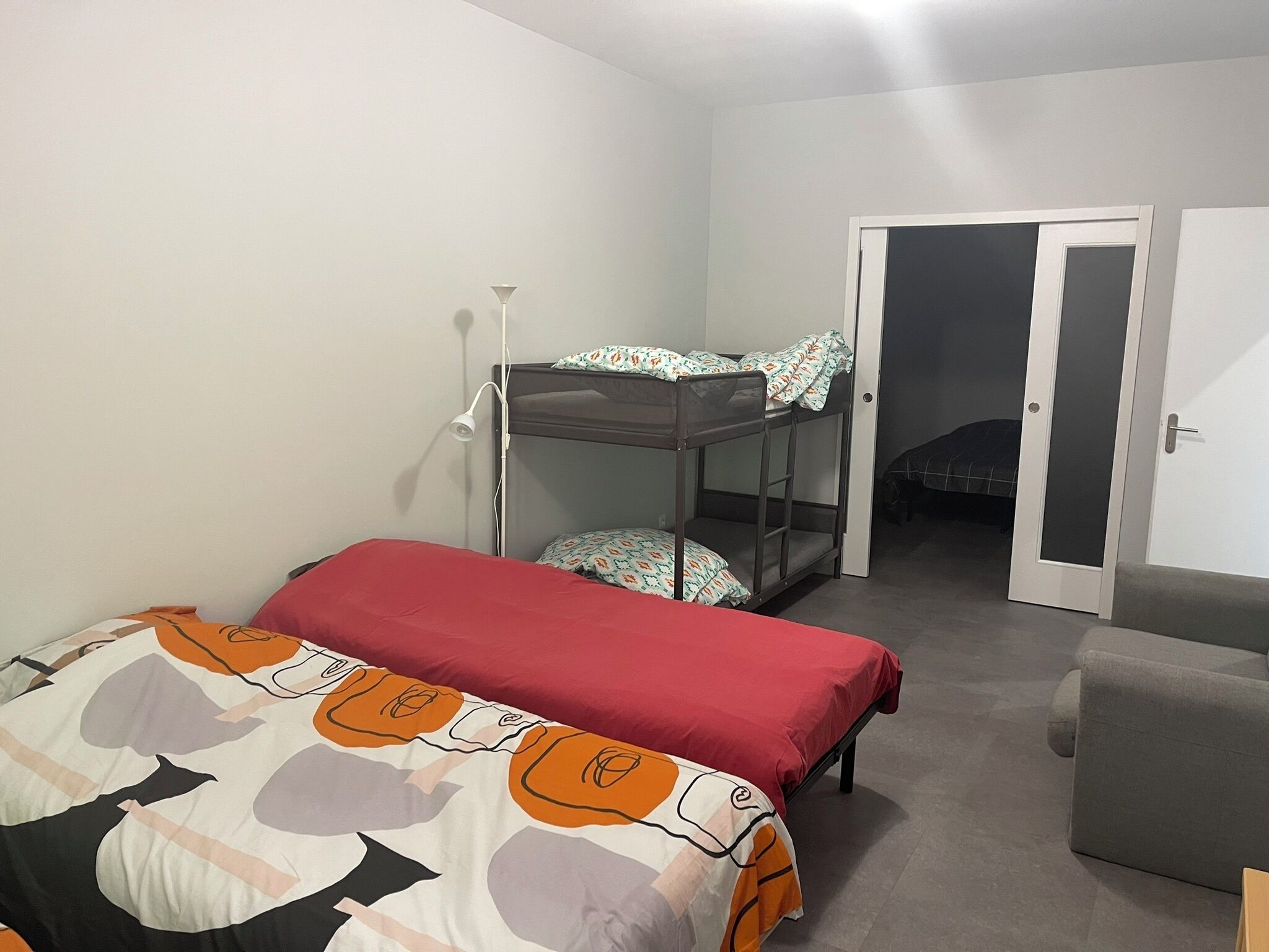 A room with bunk beds, a desk, and a chair.