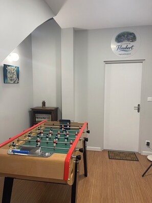 A room with a foosball table, a door, and a wall-mounted sign.