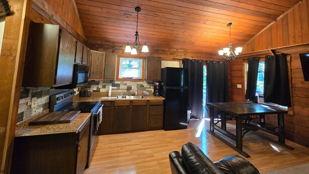 A wooden cabin interior with a kitchen, dining area, and a fireplace. - Lakefront views of Willscreek Lake 2 bedroom (Adamsville)
