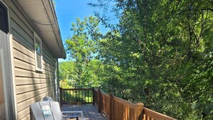 A wooden deck with two chairs and a grill, surrounded by trees and a house. - Lakefront views of Willscreek Lake 2 bedroom (Adamsville)