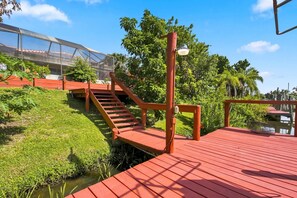 Eine Holzterrasse mit einer Treppe, die zu einem überdachten Bereich mit Glasdach führt.