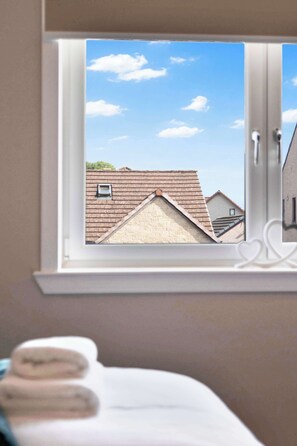 A window with a view of a building's roof and a small window.