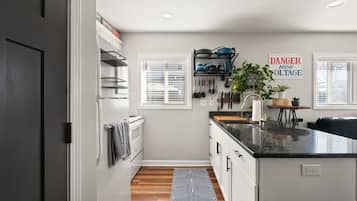 A modern kitchen with a black countertop, white cabinets, and a black and white patterned rug.