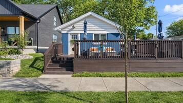 A two-story house with a covered deck, a stone retaining wall, and a well-maintained lawn.