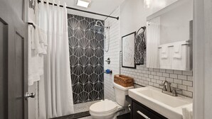 Ein Badezimmer mit Dusche, Toilette, Waschbecken und Spiegel.
