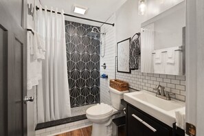 Een badkamer met een douche, toilet, wastafel en een spiegel.