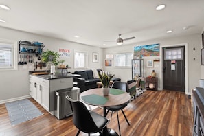 A modern kitchen with a dining area, wooden flooring, and a ceiling fan.