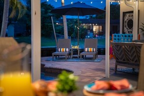 An outdoor seating area with two chairs and a table, a pool, and a view of the surrounding landscape. - Vibrant Haven: Private Dock • Games • Patio (Oakland Park)