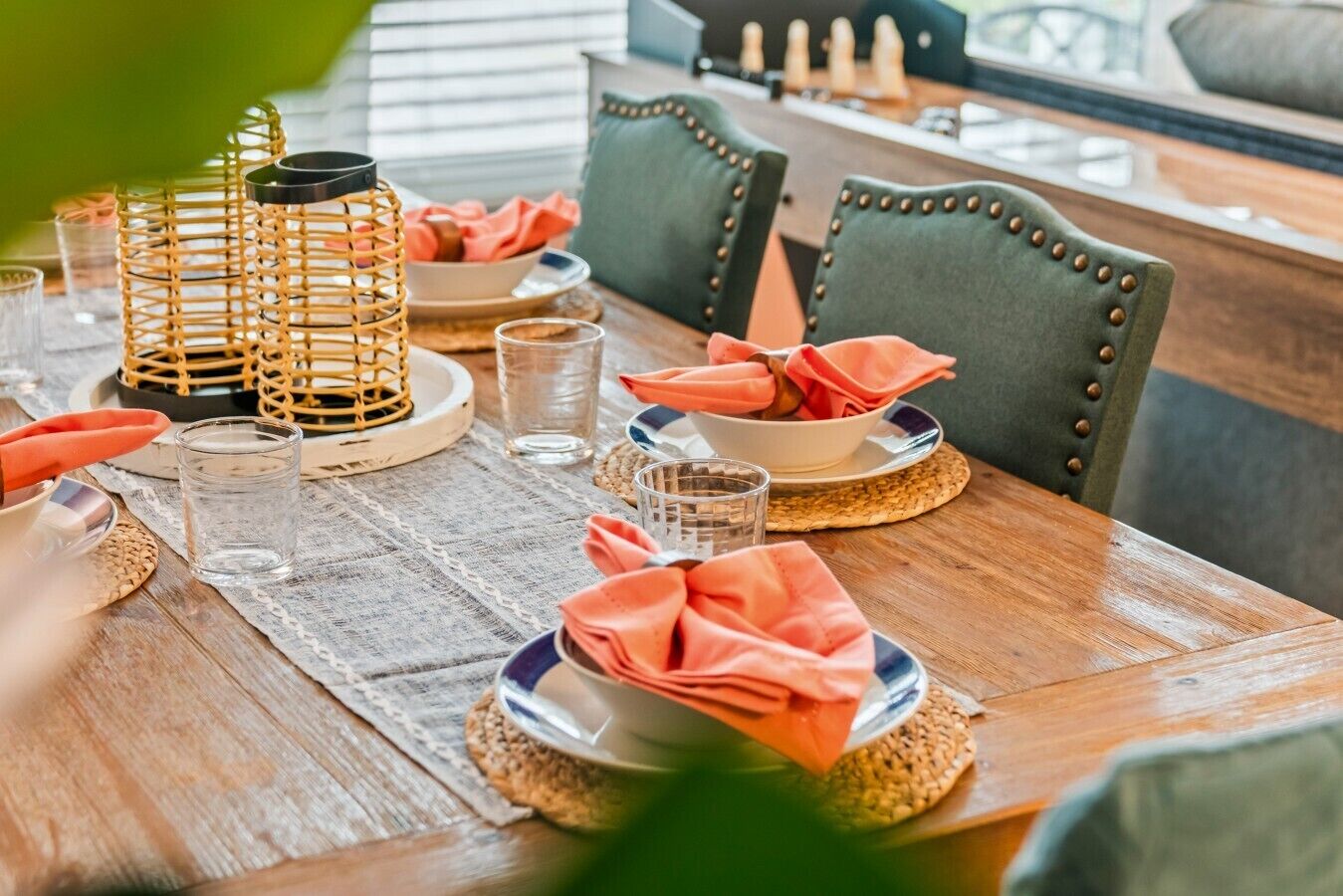 Une table à manger dressée avec des assiettes, des serviettes, des verres et un centre de table en fibres tressées.