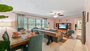 A modern living room with a dining area, a ceiling fan, and a television. - Vibrant Haven: Private Dock • Games • Patio (Oakland Park)