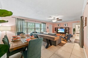 Ein modernes Wohnzimmer mit Essbereich, Deckenventilator und Fernseher.