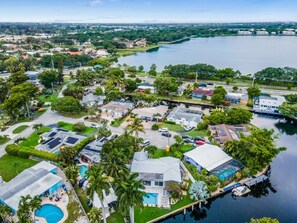 An aerial view of a residential area with houses, a swimming pool, and a body of water. - Vibrant Haven: Private Dock • Games • Patio (Oakland Park)