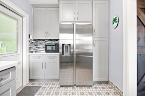 A kitchen with white cabinets, a stainless steel refrigerator, a microwave, and a toaster. - Keys Style Cottage at the edge of The Redlands (Homestead)