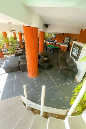 A pool table in a room with orange columns, a bar area, and a staircase leading to an outdoor area. - Escondite Teques / Alberca climatizada, diversión y espacio para grupos (Tequesquitengo)