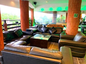 A lounge area with leather sofas, a glass coffee table, and a view of the outdoors. - Escondite Teques / Alberca climatizada, diversión y espacio para grupos (Tequesquitengo)