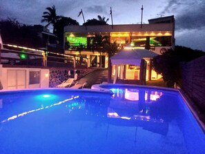 A swimming pool with a gazebo and a building with multiple floors and balconies. - Escondite Teques / Alberca climatizada, diversión y espacio para grupos (Tequesquitengo)