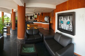 A lobby with black leather sofas, a reception desk, and a painting of a tiger's face. - Escondite Teques / Alberca climatizada, diversión y espacio para grupos (Tequesquitengo)