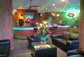 Eine Hotelhalle mit Ledersofas, einer Rezeption und dekorativen Blumenarrangements.