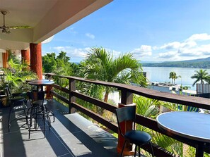 An outdoor seating area with tables and chairs, overlooking a body of water and greenery. - Escondite Teques / Alberca climatizada, diversión y espacio para grupos (Tequesquitengo)